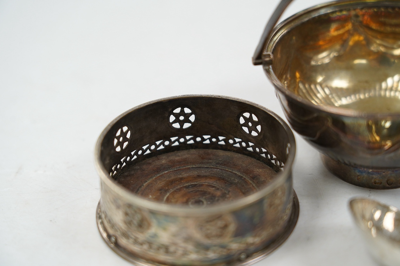 A George III silver small epergne basket, London, 1800, diameter 80mm, a large William IV silver caddy spoon and an Old Sheffield plate sauce bottle coaster. Condition - fair